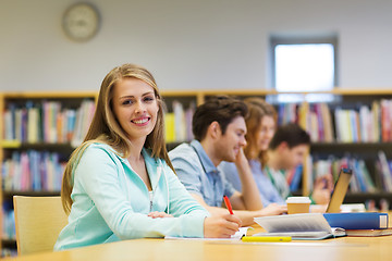 Image showing happy student girl writing to notebook in library