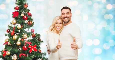 Image showing happy couple showing thumbs up with christmas tree