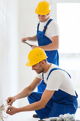 Image showing builders with tablet pc and fixing wiring indoors