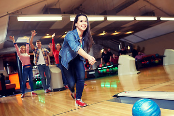 Image showing happy young woman throwing ball in bowling club