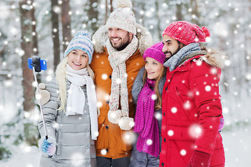 Image showing smiling friends with smartphone in winter forest