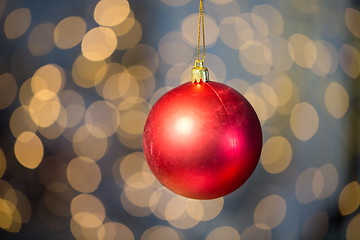 Image showing close up of red christmas ball over golden lights