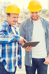 Image showing smiling builders with tablet pc outdoors