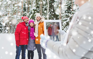 Image showing smiling friends with tablet pc in winter forest