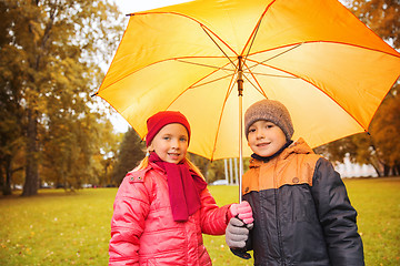 Image showing happy boy and girl with umbrella in autumn park