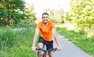 Image showing happy young man riding bicycle outdoors