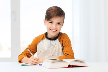 Image showing smiling student boy writing to notebook at home