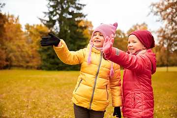 Image showing two happy little girls waving hand in autumn park