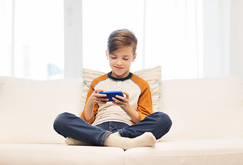 Image showing boy with smartphone texting or playing at home