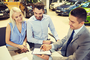 Image showing happy couple with car dealer in auto show or salon