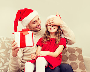 Image showing smiling father surprises daughter with gift box