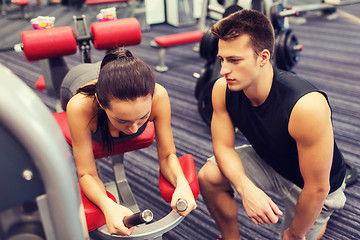 Image showing young woman with trainer exercising on gym machine