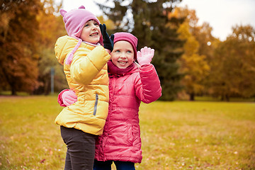 Image showing happy little girls waving hands in autumn park