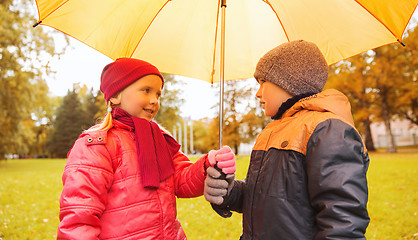 Image showing happy boy and girl with umbrella in autumn park