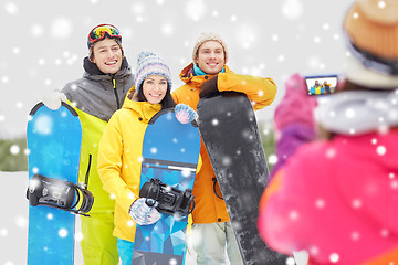 Image showing happy friends with snowboards and smartphone