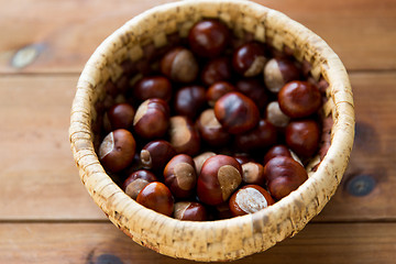 Image showing close up of chestnuts in basket on wooden table