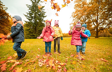 Image showing happy children playing with autumn leaves in park