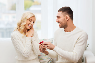 Image showing happy man giving engagement ring to woman at home