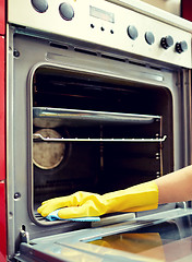 Image showing close up of woman cleaning oven at home kitchen