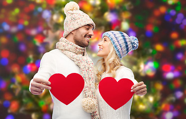 Image showing smiling couple in winter clothes with red hearts