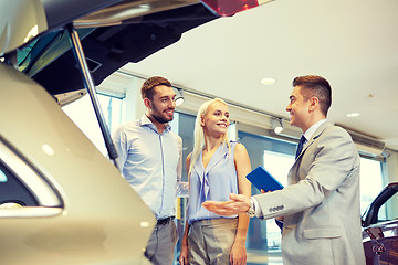 Image showing happy couple with car dealer in auto show or salon