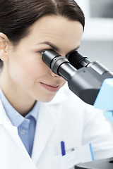 Image showing close up of scientist looking to microscope in lab