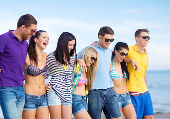 Image showing group of happy friends walking along beach