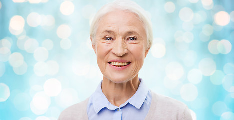 Image showing happy senior woman face over blue lights