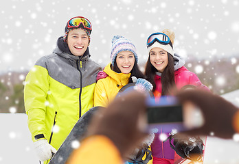 Image showing happy friends with snowboards and smartphone