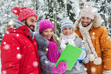 Image showing smiling friends with tablet pc in winter forest