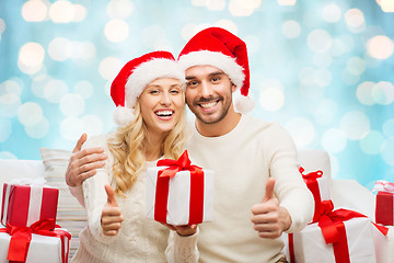 Image showing happy couple with christmas gifts and thumbs up