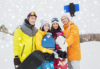 Image showing happy friends with snowboards and smartphone