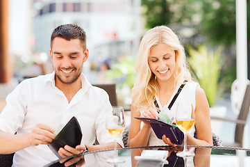 Image showing happy couple with wallet paying bill at restaurant