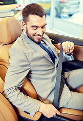 Image showing happy man sitting in car at auto show or salon