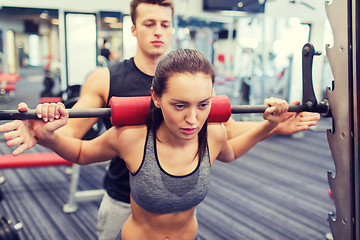 Image showing man and woman with barbell flexing muscles in gym