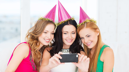 Image showing three smiling women in hats having fun with camera