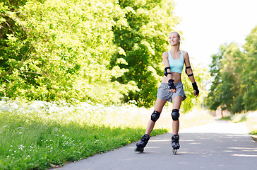 Image showing happy young woman in rollerblades riding outdoors