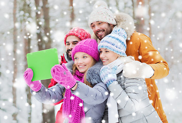 Image showing smiling friends with tablet pc in winter forest