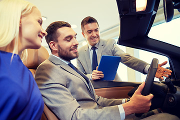 Image showing happy couple with car dealer in auto show or salon