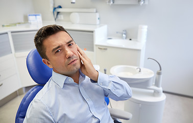 Image showing man having toothache and sitting on dental chair