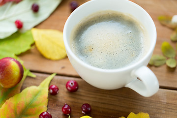 Image showing close up of coffee cup on table with autumn leaves