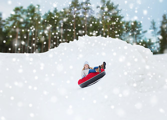 Image showing happy teenage girl sliding down on snow tube