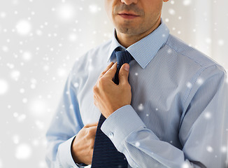 Image showing close up of man in shirt adjusting tie on neck