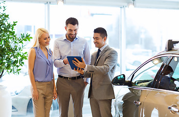 Image showing happy couple with car dealer in auto show or salon