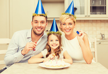 Image showing smiling family in blue hats blowing favor horns