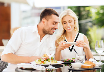 Image showing happy couple with smatphone photographing food