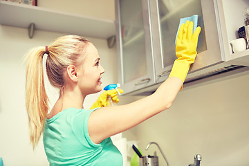 Image showing happy woman cleaning cabinet at home kitchen