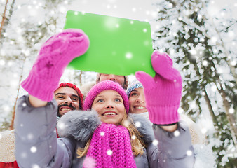 Image showing smiling friends with tablet pc in winter forest