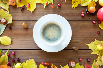 Image showing close up of coffee cup on table with autumn leaves