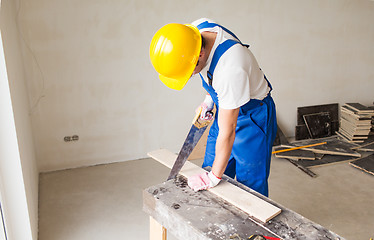 Image showing close up of builder with arm saw sawing board